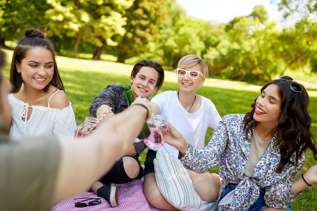 Zdjęcie szczęśliwi przyjaciele pijący drinki w letnim parku.