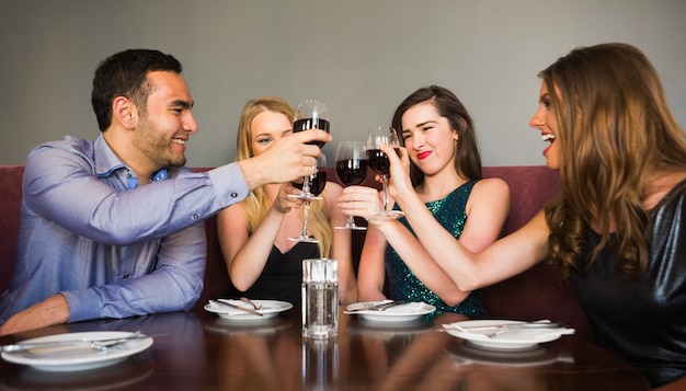 Szczęśliwi przyjaciele pije czerwone wino w barze