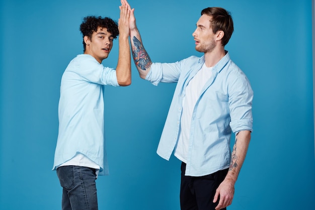 Szczęśliwi przyjaciele w identycznych koszulach uściskają sobie ręce na niebieskim tle komunikacja Zdjęcie wysokiej jakości
