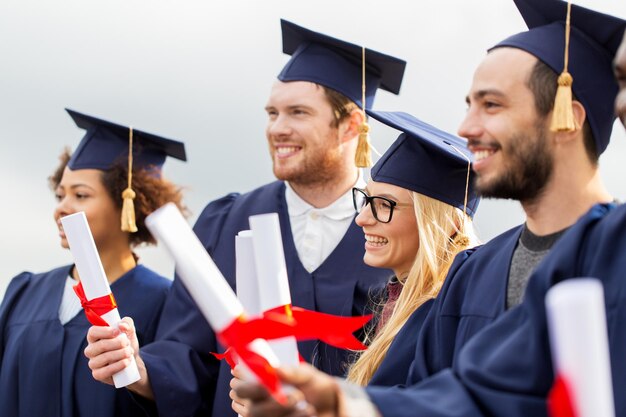 Zdjęcie szczęśliwi studenci na deskach z moździerzem z dyplomami