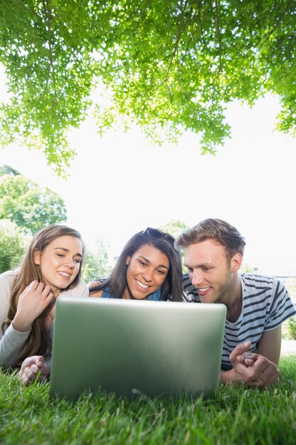 Szczęśliwi ucznie używa laptop na zewnątrz