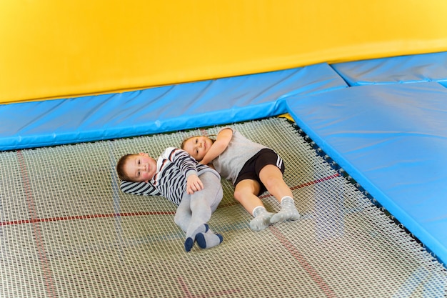 Szczęśliwi Uśmiechnięci Mali Dzieciaki Kłaść Na Salowym Trampoline W Centrum Rozrywki