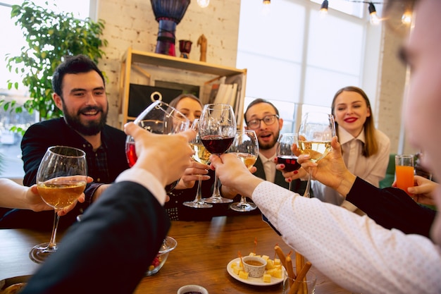 Zdjęcie szczęśliwi współpracownicy świętują podczas imprezy firmowej i imprezy firmowej. młodzi ludzie rasy kaukaskiej w strojach biznesowych doping, śmiejąc się. pojęcie kultury biurowej, pracy zespołowej, przyjaźni, wakacji, weekendu.