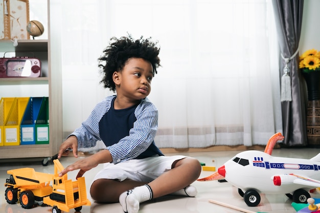 Szczęśliwy African American Dziecko Gra Ciężarówka I Zabawka Samolot Powietrzny W Domu