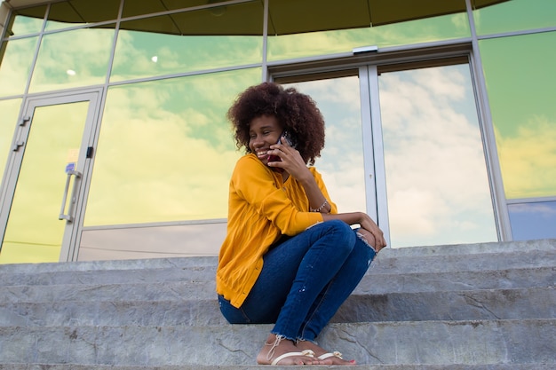 Szczęśliwy African American kobieta na ulicy rozmawia przez telefon