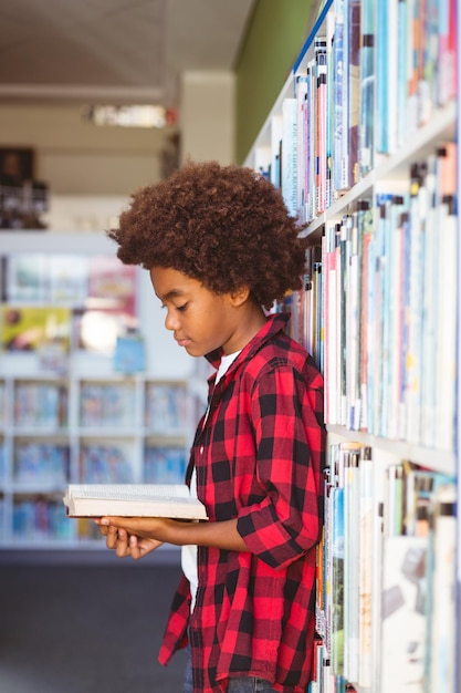 Szczęśliwy african american uczeń czytania książki stojąc w bibliotece szkolnej