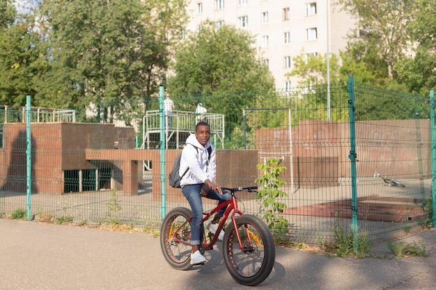 Szczęśliwy Afroamerykanin jeździ na rowerze przez publiczny park Sport i rekreacja