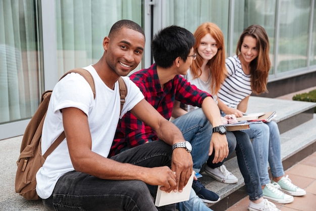 Szczęśliwy afroamerykanin młody student siedzący ze swoimi frytkami na zewnątrz