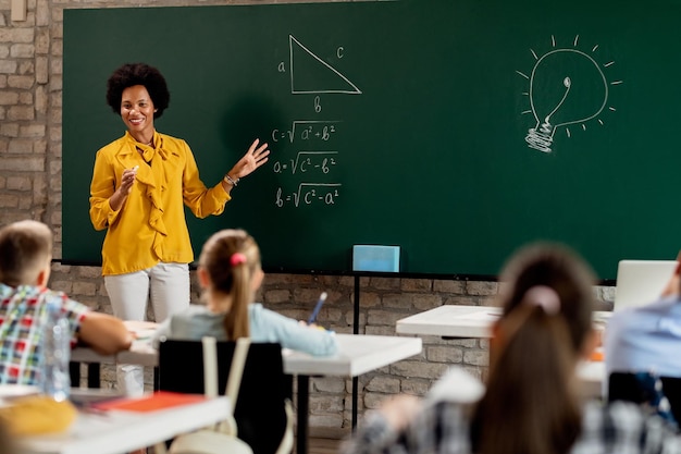 Szczęśliwy Afroamerykanin nauczyciel matematyki wyjaśniający wykład na tablicy w klasie