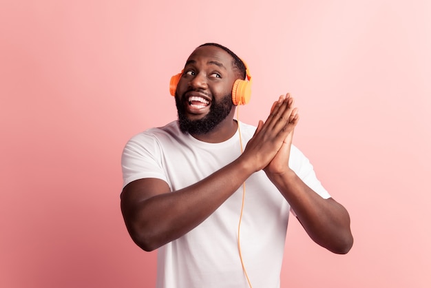 Szczęśliwy afrykański mężczyzna uśmiechający się słuchając muzyki w słuchawkach trzymaj ręce wyglądają na pustą przestrzeń
