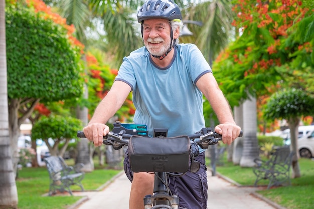 Szczęśliwy aktywny starszy mężczyzna na rowerze w publicznym parku z elektrycznym rowerem cieszącym się wolnością Koncepcja zdrowego stylu życia i zrównoważonej mobilności