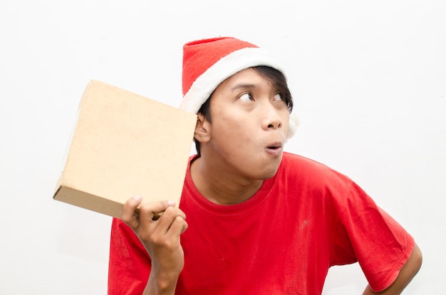 szczęśliwy atrakcyjny azjatycki człowiek w czerwonych świątecznych ubraniach tematycznych wskazując palcem i prezentując coś.