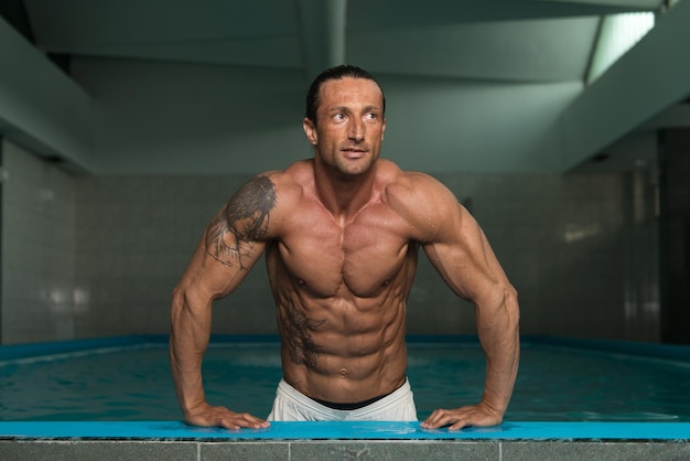 Szczęśliwy atrakcyjny muskularny dojrzały mężczyzna odpoczywający zrelaksowany na krawędzi basenu