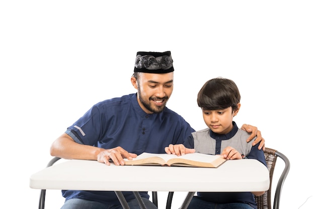 Szczęśliwy azjatycki ojciec i syn czytają razem Koran na białym tle