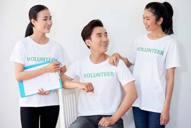 Szczęśliwy Azjatycki Zespół Młodych Wolontariuszy Uśmiechający Się I Patrzący Na Siebie