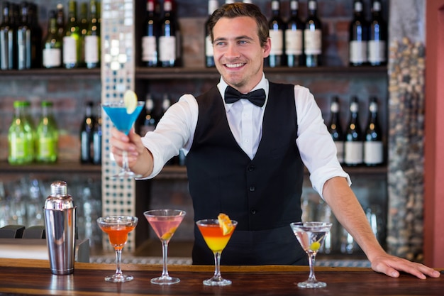 Szczęśliwy barman serwujący niebieskie martini