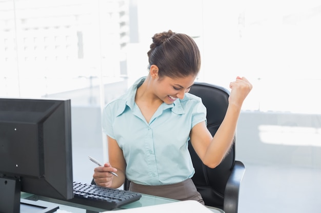 Szczęśliwy bizneswoman przed komputerem w biurze