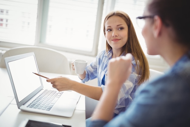 Szczęśliwy bizneswoman wskazuje na laptopie z kolegą w biurze