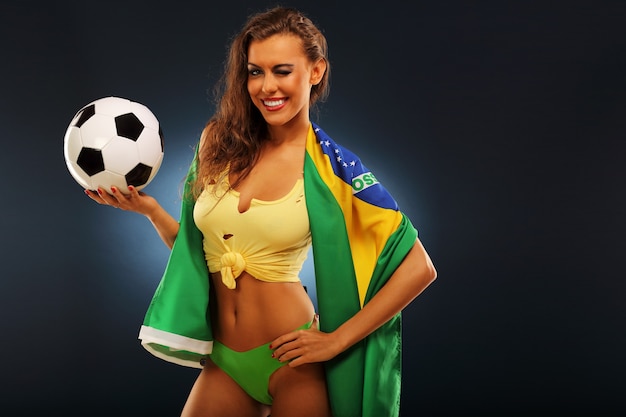 Szczęśliwy brazylijski kibic dopingujący flagą i piłką nożną
