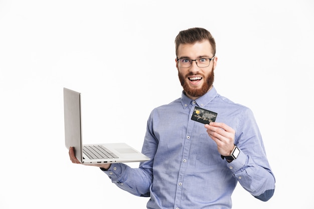 Szczęśliwy Brodaty Elegancki Mężczyzna W Okularach Trzymający Laptopa I Kartę Kredytową Podczas Patrzenia
