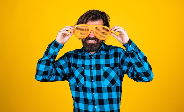 szczęśliwy brodaty facet w śmiesznych okularach imprezowych i koszuli w kratkę na żółtym tle pozwala świętować
