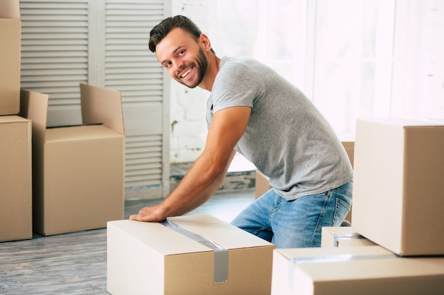 Szczęśliwy brodaty mężczyzna pakuje karton do swojego nowego mieszkania