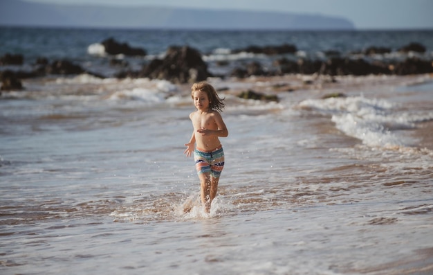 Szczęśliwy chłopiec biegający po plaży nad morzem podekscytowany zdumiony dzieciak bawiący się bieganiem przez wodę w