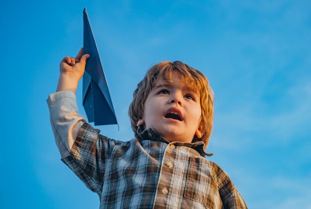 Szczęśliwy chłopiec dziecko działa na łące z samolocikiem w lecie w przyrodzie. Mały ładny chłopiec gra