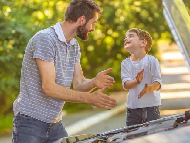 Zdjęcie szczęśliwy chłopiec i ojciec naprawiają samochód