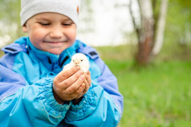 Szczęśliwy chłopiec mały rolnik trzyma w rękach kurczaka noworodka