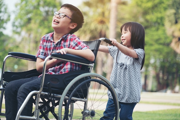 Zdjęcie szczęśliwy chłopiec na wózku inwalidzkim z dziewczyną spróbuj jazdy na wózku inwalidzkim z jej brata uśmiech