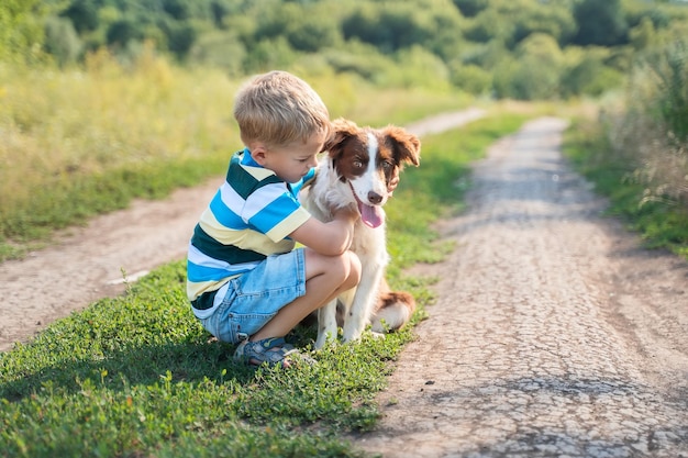 Zdjęcie szczęśliwy chłopiec przytulający brązowy i biały border collie