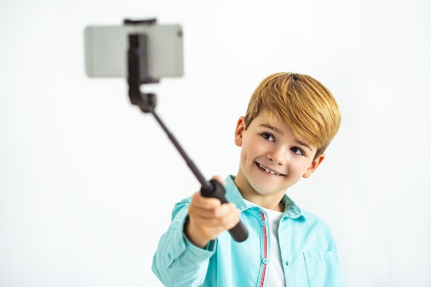 Szczęśliwy chłopiec robi selfie na białym tle
