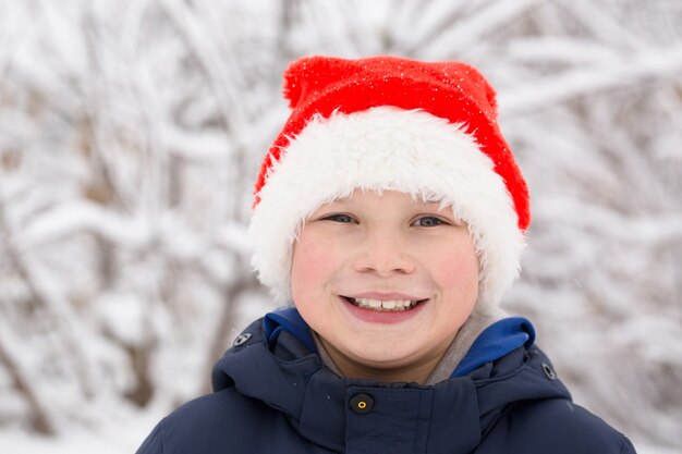 Szczęśliwy chłopiec w santa hat na ulicy w zimie