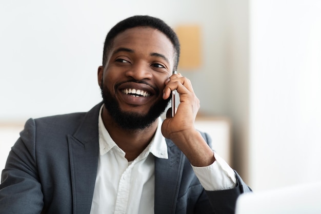 Szczęśliwy czarny biznesmen rozmawia przez telefon w biurze