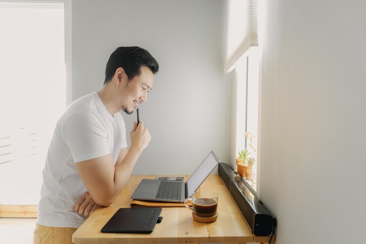 Szczęśliwy człowiek freelancer pracuje na swoim laptopie. Koncepcja niezależnych prac twórczych.