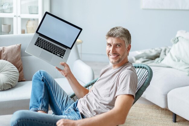 Szczęśliwy człowiek pokazujący swój nowy widok z boku laptopa