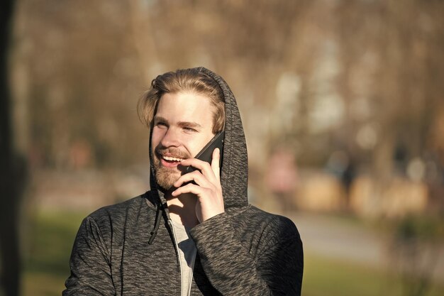 Szczęśliwy człowiek rozmawia przez telefon komórkowy w komunikacji parku
