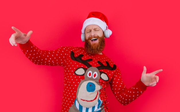 Zdjęcie szczęśliwy człowiek świętuje boże narodzenie tańcząc do muzyki bearded santa claus śpiewa do muzyki