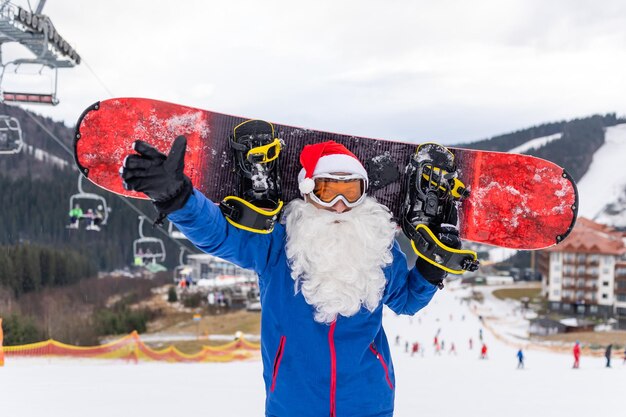 Szczęśliwy Człowiek W Czerwonym Kapeluszu Bożonarodzeniowym Santa Ze Snowboardem Na Wzgórzu Zimowych Gór