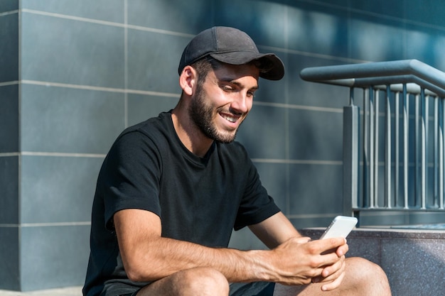 Szczęśliwy człowiek wysyła SMS-y na smartfonie na ulicy