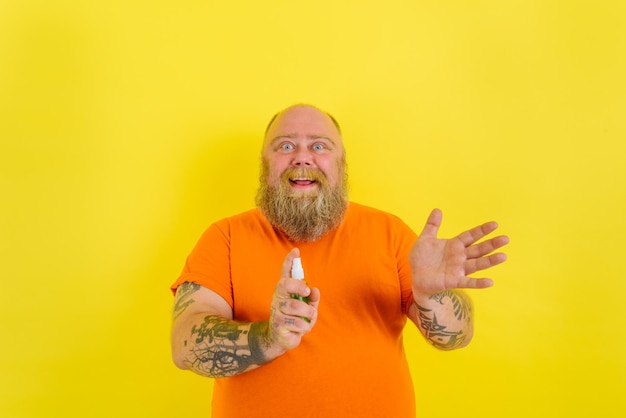 Zdjęcie szczęśliwy człowiek z brodą i tatuażami trzyma środek do czyszczenia rąk przeciwko covid
