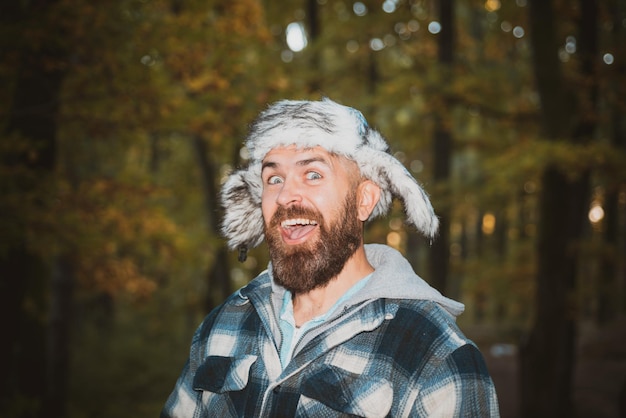 Szczęśliwy człowiek z brodą w jesiennym parku portret uśmiechniętego młodego mężczyzny w ciepłym ubraniu, drżący podczas