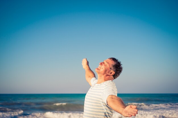 Szczęśliwy człowiek z otwartymi rękami na tle błękitnego morza i nieba Senior zabawy na wakacjach Koncepcja wolności i wyobraźni