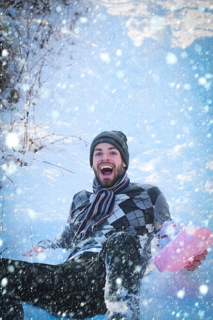 Zdjęcie szczęśliwy człowiek z prezentem leżącym na śniegu