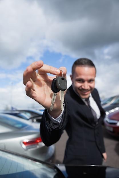 szczęśliwy dealer trzyma kluczyki do samochodu za opuszkami palców