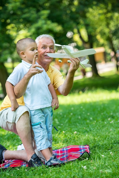 Zdjęcie szczęśliwy dziadek i dziecko bawią się i bawią w parku w piękny słoneczny dzień