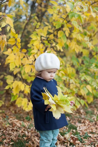 Szczęśliwy dzieciak cieszy się jesienną pogodą. mała dziewczynka w jesiennych liściach.