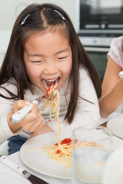 Szczęśliwy dzieciak cieszy się spaghetti lunch w kuchni