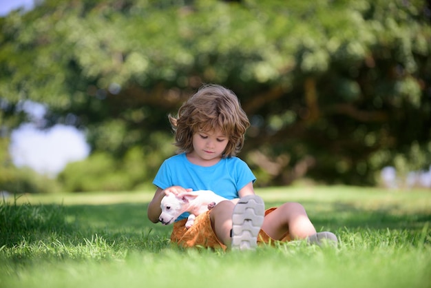 Szczęśliwy dzieciak przytulający pięknego szczeniaka pies młody chłopiec dzieciak bawiący się ze szczeniakiem i siedzący na trawie słodki chłopak